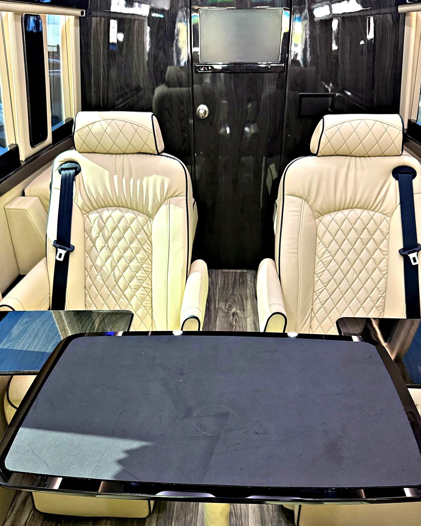 Front-to-rear view of the Jet-Style Sprinter cabin — quilted captain's chairs, the onboard Samsung display for casting presentations, and the central pre-installed conference table